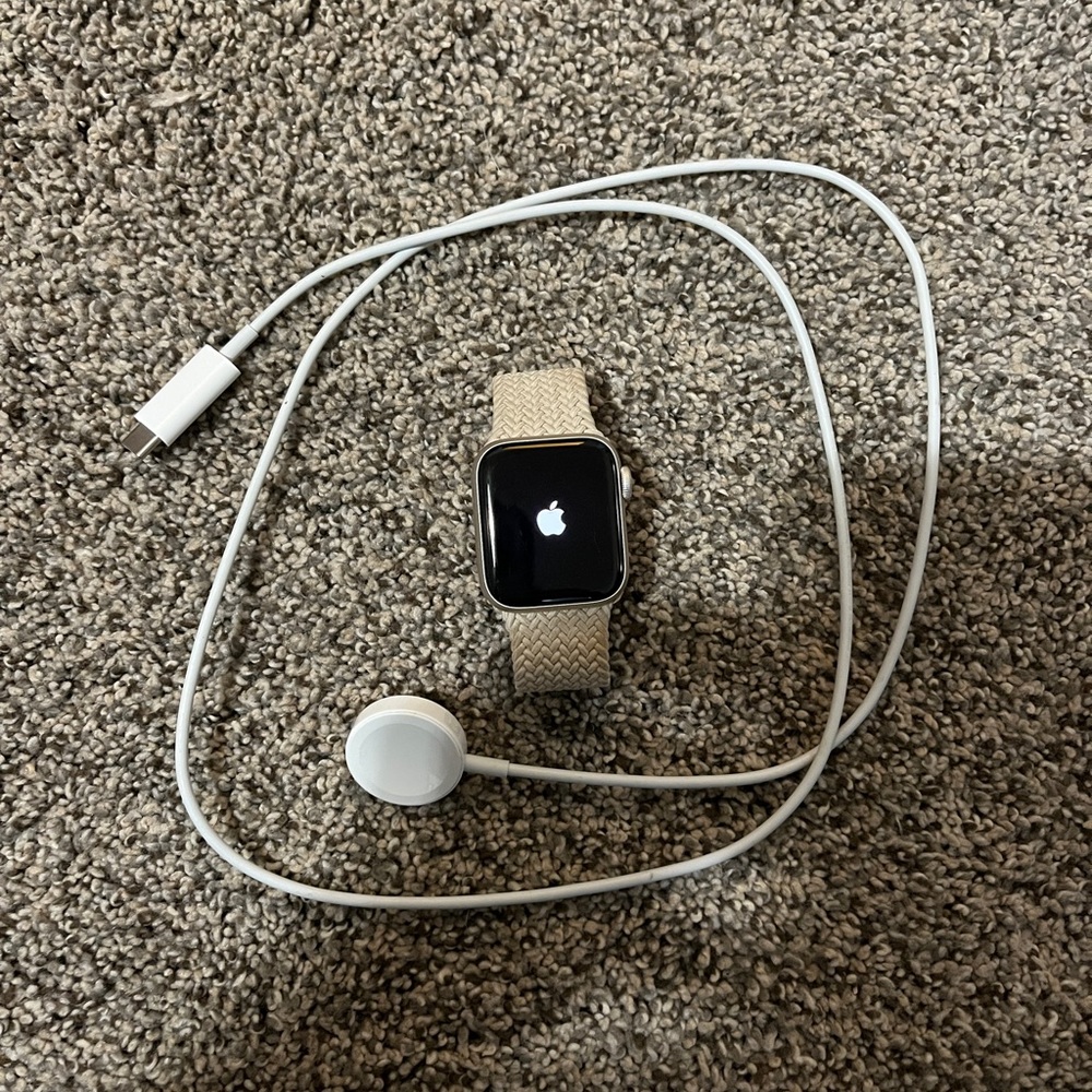 Apple Watch SE with stretchy tan cream band and charger